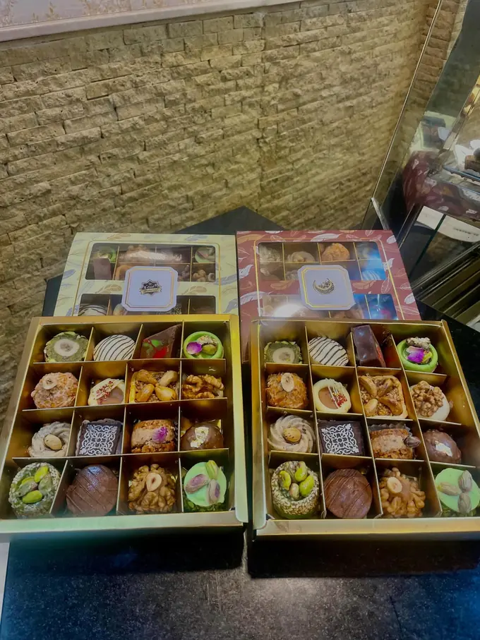 Nos coffrets de pâtisseries assorties, présentés ici avec un ruban « Eid Mubarak ».