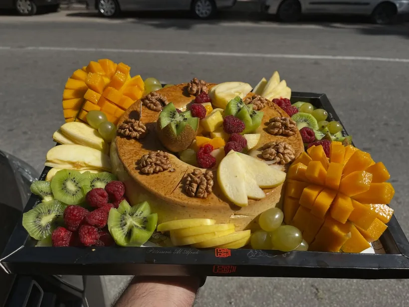 Notre gâteau aux fruits frais : fraises, kiwi, pêche et raisin disposés sur une crème claire.
