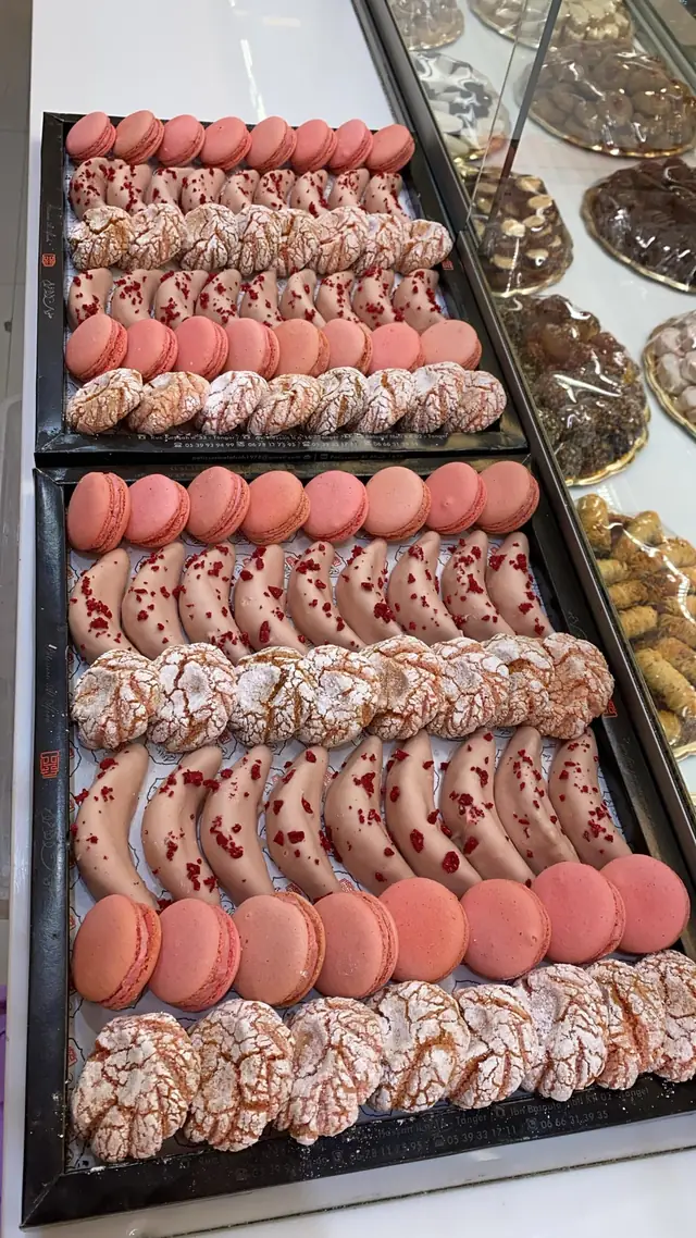 Macarons roses et sablés craquelés, rangés côte à côte au comptoir.